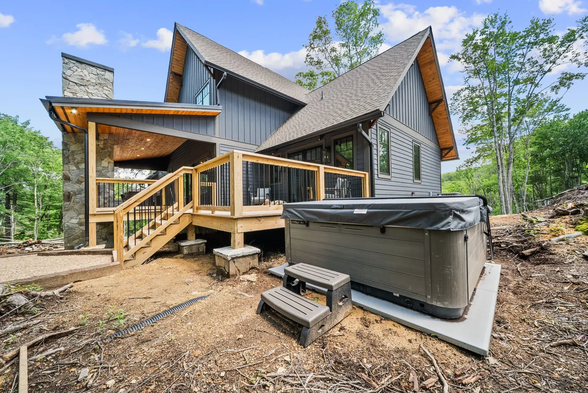 An inviting hot tub sits on a spacious deck attached to the house, with architectural elements of the home visible in the background. The setting conveys a tranquil atmosphere, perfect for soaking under the stars or relaxing after a day outdoors.