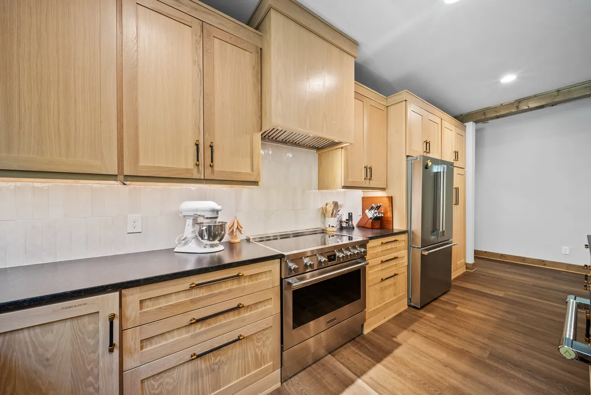 A focused view of the kitchen’s granite countertops, sleek stainless steel oven, and custom wooden cabinetry. Countertop appliances and well-organized storage illustrate the kitchen’s functionality and aesthetic appeal.